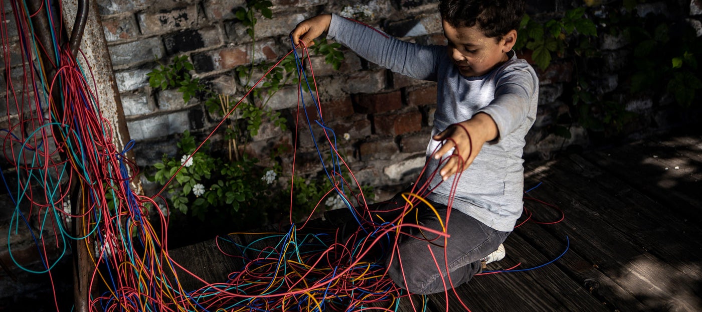 a child playing with a pile of multicolored shoe laces