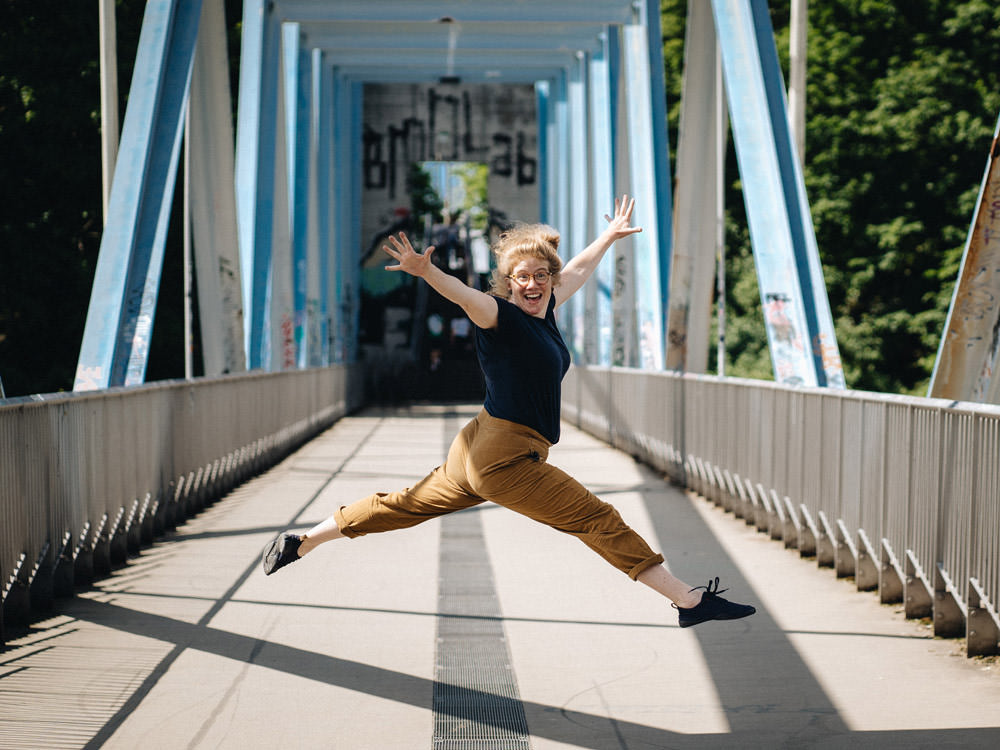 smiling woman jumps into the air wearing wildling shoes