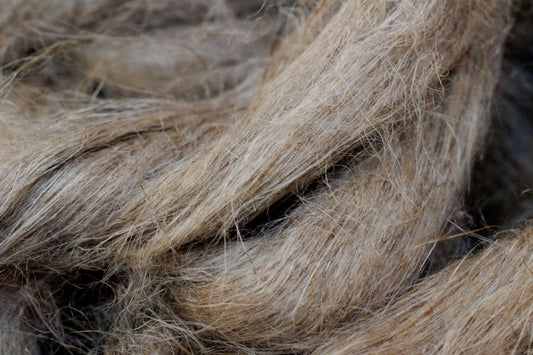 Several strands of flax fiber in various shades between beige and dark gray.